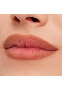 Matowe, nagie usta z łagodnym gradientem od ciemniejszego do jaśniejszego odcienia; gładka tekstura; zbliżenie koncentrujące się na kształcie i szczegółach warg.