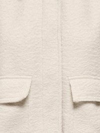 Manteau blanc texturé avec deux poches plaquées externes, présentant une surface douce et duveteuse ainsi qu'un design épuré et droit. Aucune quincaillerie visible.