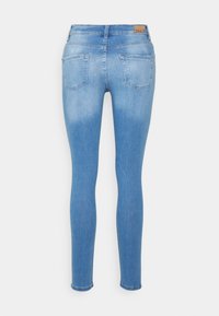 Jeans skinny em denim azul claro com efeito desbotado. Apresenta dois bolsos traseiros e uma etiqueta na cintura. Textura suave e design ajustado.