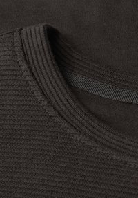 Primo piano di tessuto a costine grigio scuro che mostra la scollatura e il motivo lavorato a maglia della veste.