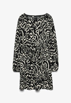 Zwart-witte jurk met lange mouwen met abstracte draaipatronen en diamantvormen, voorzien van een stoffen ceintuur die in een strik is gebonden bij de taille.