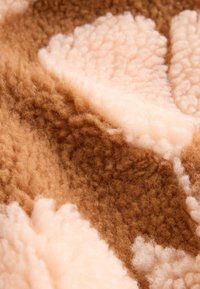 Gestructureerde stof met een zachte, pluizige uitstraling, met een patroon van lichtbruine en crèmekleurige vormen. Warme, gezellige en tastbare oppervlakte.