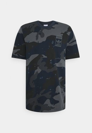 Ciemna koszulka Adidas z krótkim rękawem w kamuflażowy wzór z naszywką z logo na lewej piersi na białym tle.