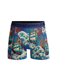 Blå boxerkalsonger med ett mönster av fartyg och bläckfiskar bland svallande vågor, med en svart midjeband märkt "MUCHACHOMALO."