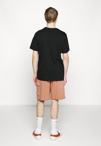 Nike Sportswear CLUB CARGO - Calças de fato de treino - mineral clay/white