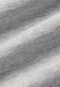 Szary dziany materiał z teksturowanym wzorem, prezentujący miękką, lekko wypukłą powierzchnię oraz nieregularny splot, zaprojektowany z myślą o komforcie i elastyczności.