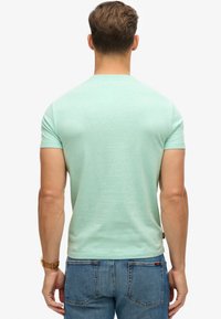 T-shirt verde menta a maniche corte con collo rotondo, realizzato in tessuto leggero e dalla vestibilità rilassata. Abbinato a jeans in denim blu.