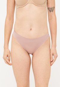 Svetloružové bezšvové spodné prádlo s hladkým povrchom a minimalistickým dizajnom. Má nízky strih a mäkký elastický pás.