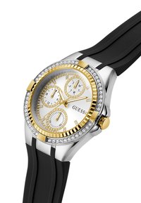 Montre en or et en argent avec un cadran blanc, trois sous-cadrans et des accents en cristal. Équipée d'un bracelet en caoutchouc noir et d'un boîtier en acier inoxydable.