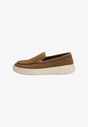 Mocassin slip-on en daim marron avec une épaisse semelle en caoutchouc blanc et des détails cousus le long du bord supérieur.