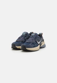 Marineblaue Sportschuhe aus Mesh- und Wildledermaterialien, mit einer Gummisohle, strukturierten Schnürsenkeln und einem silbernen Nike-Swoosh an der Seite.