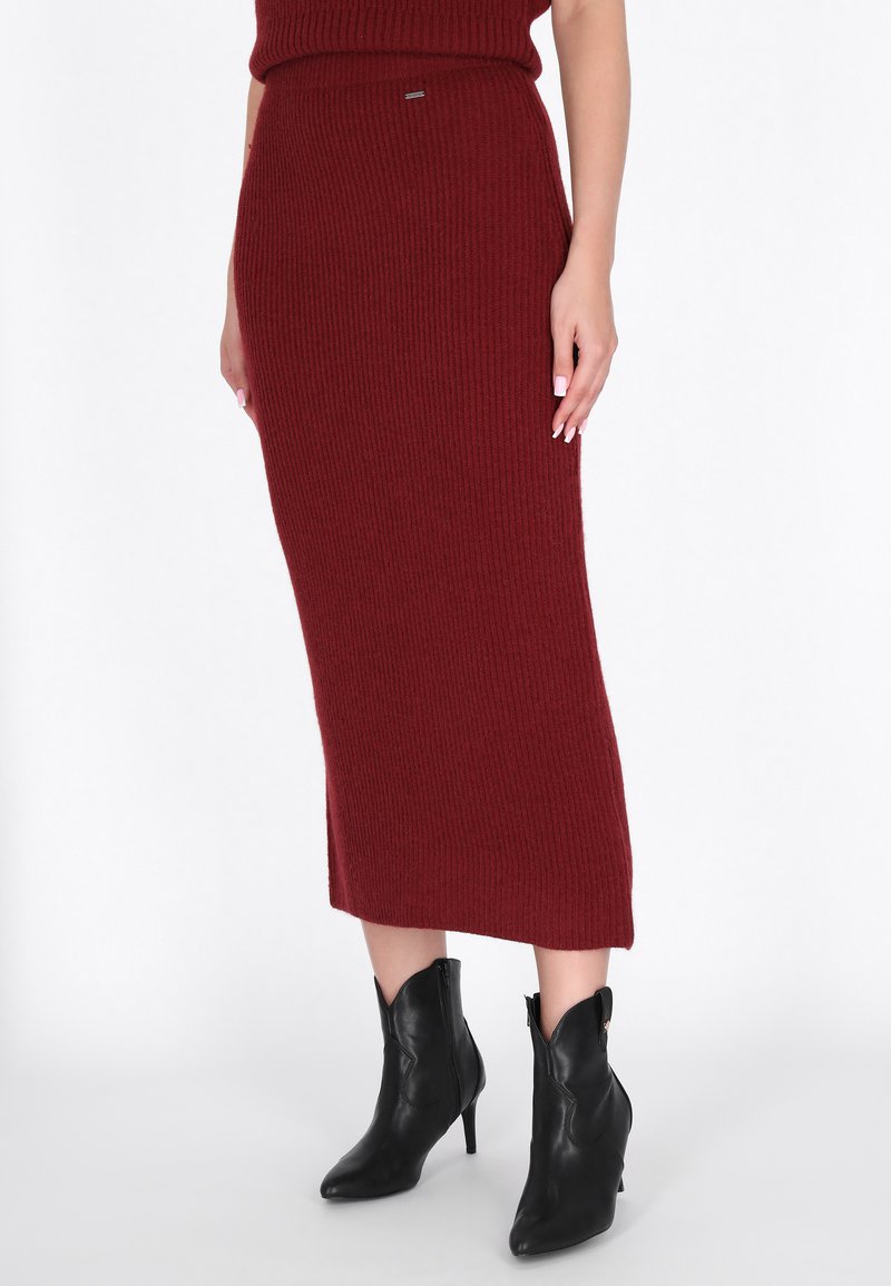 Burgundi ribbed kötött midi szoknya magas derékkal, fekete stiletto bokacsizmával párosítva, amelynek hegyes orra és kivágott dizájnja van.