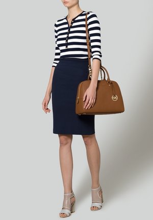 Marineblauwe en witte gestreepte langemouwen top, marineblauwe kokerrok, beige handtas met gouden hardware en naaktkleurige hakken.
