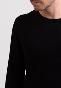 Maglione nero a maglia con scollatura rotonda e maniche lunghe, caratterizzato da una texture morbida e un design minimale, che mette in risalto il materiale di qualità.