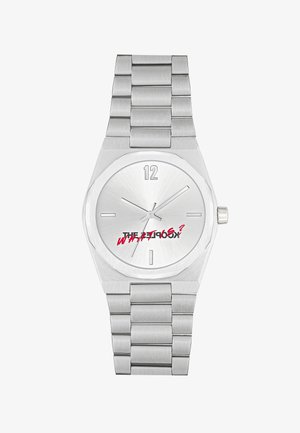 Reloj de acero inoxidable plateado con pulsera de metal cepillado, caja octagonal, esfera minimalista y letras rojas en negrita en la carátula.