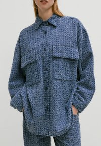 Blauwe gestructureerde button-up shirt met twee borstzakken, een puntkraag en lange mouwen, gemaakt van een pluizige, geweven stof.