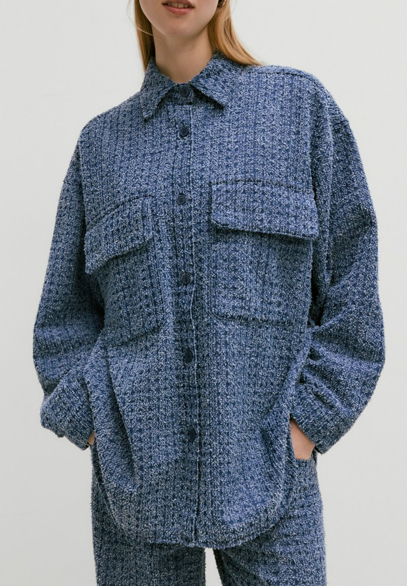 Blauwe gestructureerde button-up shirt met twee borstzakken, een puntkraag en lange mouwen, gemaakt van een pluizige, geweven stof.