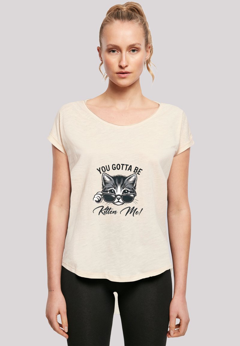 Helle beige Kurzarm-T-Shirt mit Rundhalsausschnitt, das ein Grafik eines Katzen mit Sonnenbrille zeigt und den Text "DU MUSST WIE EIN Kätzchen SEIN!" enthält.