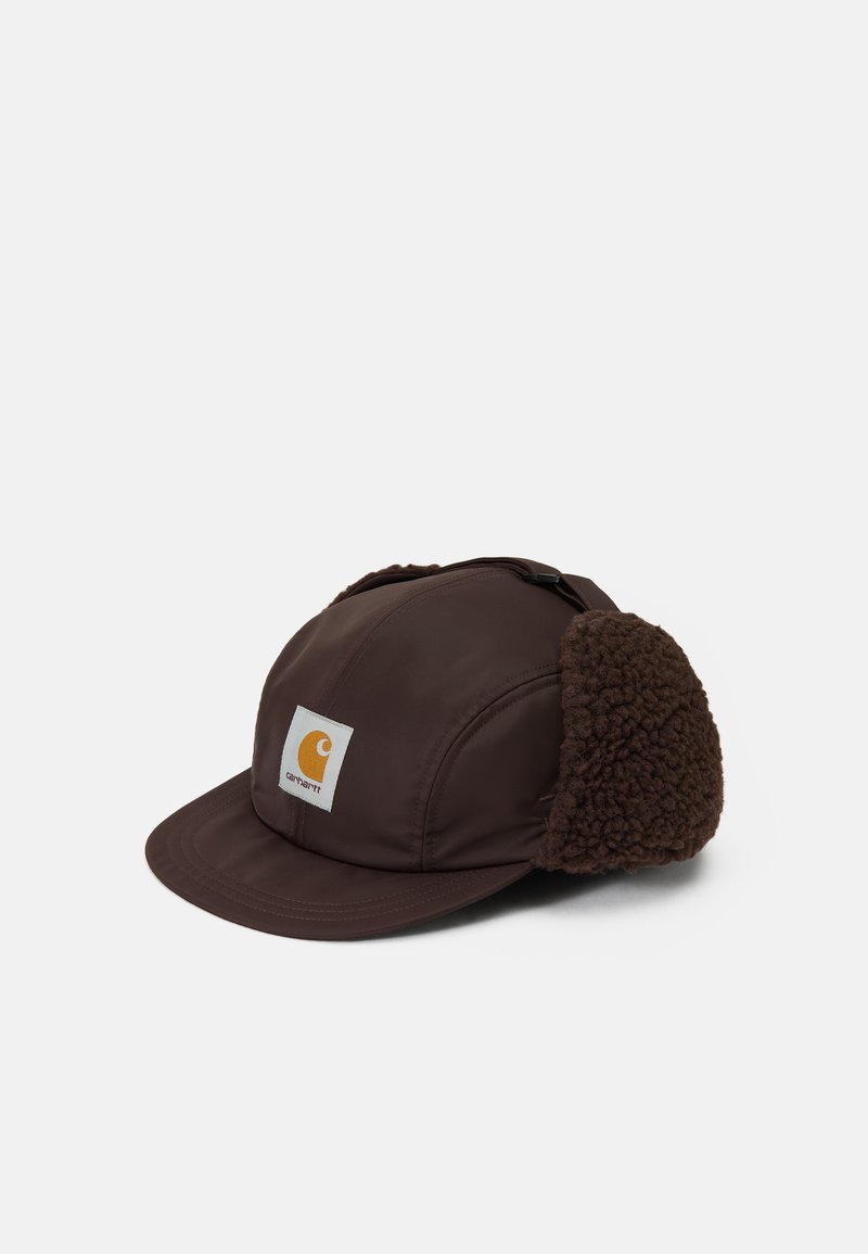 Cappello marrone in tessuto liscio con visiera piatta, dotato di paraorecchie in fleece marrone e una toppa bianca con un logo arancione sul davanti.