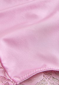 Material de satin roz delicat, neted cu dantelă fină de-a lungul marginii, arătând pliuri moi și detalii ale cusăturilor.