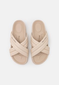 Sandales à glissière beiges avec des lanières croisées. Fabriquées en matériau synthétique lisse, elles présentent une semelle intérieure profilée et un logo de marque embossé.