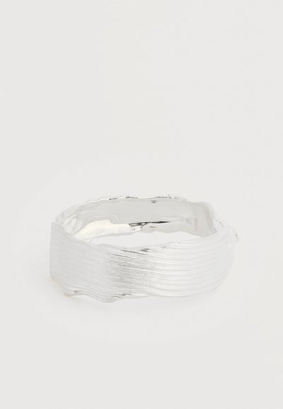 Δαχτυλίδι από ασημί με υφή, κυματιστή, βουρτσισμένη επιφάνεια και οργανικό, ανομοιόμορφο σχέδιο σε απλό φόντο.