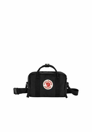 Kleine schwarze Fjällräven Kånken Tasche mit oberen Griffen, verstellbarem Schultergurt und vorderem Logo-Patch in Rot und Weiß.