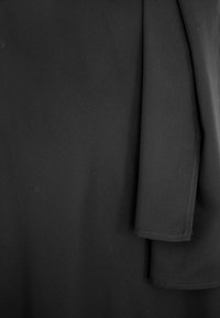 Czarna tkanina o gładkiej teksturze, z fałdą w drapowaniach i czystymi krawędziami. Materiał wydaje się lekki i elastyczny.