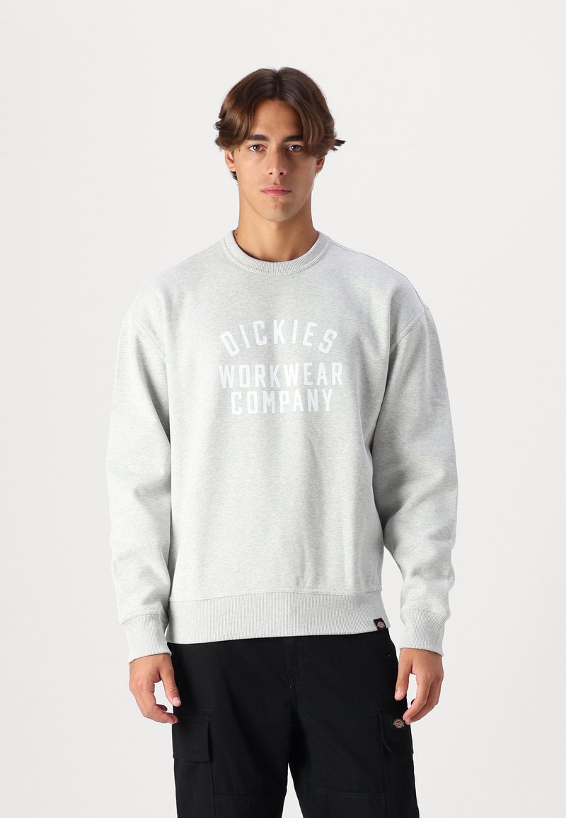 Felpa grigia chiara con polsini e bordo a coste, caratterizzata da un audace logo bianco "DICKIES WORKWEAR COMPANY" sul davanti.