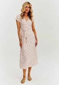 Różowa sukienka typu wrap w niebieskie kropki, krótki rękaw, z wiązaniem w talii i zwiewnym midi długości. Gładki materiał o lekkiej fakturze.