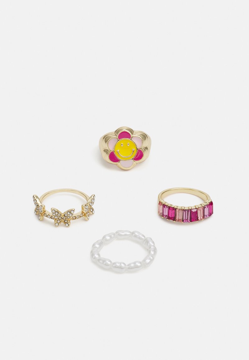 Quatro anéis: um anel de flor dourada com um sorriso amarelo, um design de borboleta com strass, um anel de contas texturizadas em rosa e uma corrente de pedra rosa.
