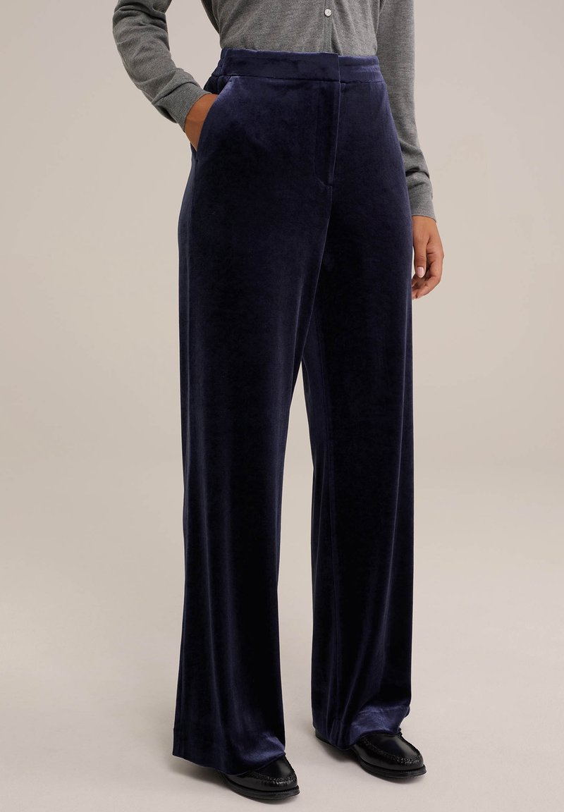 Navy velvet wide-leg pants with side pockets, soft texture, high waist, and flowing design. Paired with a gray long-sleeve top.