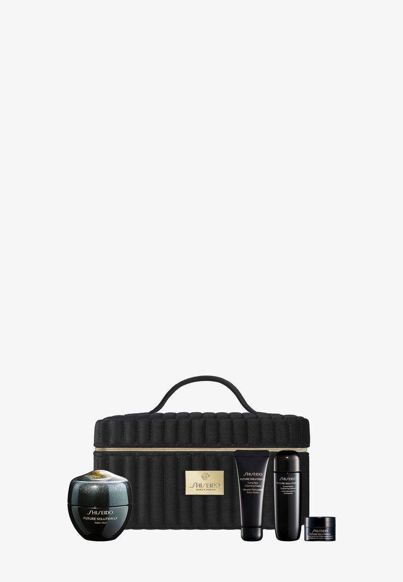Custodia da viaggio nera trapuntata con logo dorato; contiene quattro prodotti skincare Shiseido: un barattolo di crema, due tubetti e un barattolo piccolo.