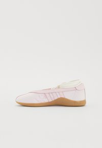 Sapatilha de tecido rosa claro com uma textura suave, apresentando uma sola de borracha e um design com atacadores. Inclui três riscas verticais de lado.