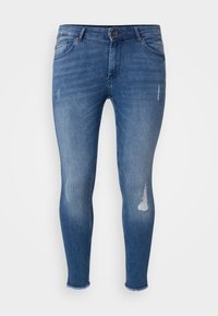 Smala blå jeans i denim med slitna detaljer, en standard midjeresår och fransiga fållar. Tyget har en mjuk, lätt sliten textur.
