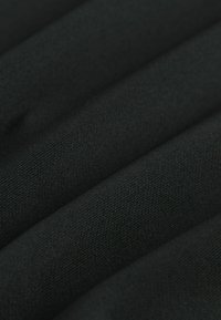 Black fabric with a textured surface, showing fine weaves and folds. The material appears soft and lightweight.