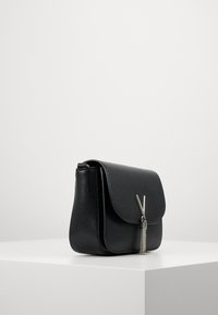 Borsa a spalla in pelle nera con finitura testurizzata, chiusura a patta e accento in catena argentata. Design compatto e rettangolare con una silhouette elegante.