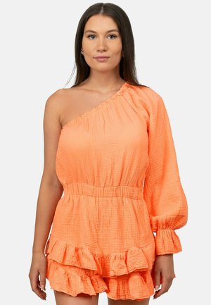 Femme portant une robe orange vif à une épaule avec une manche longue bouffante, une taille élastique et une jupe à volants superposés.