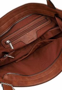Intérieur d'un sac à main en cuir brun présentant plusieurs compartiments, une poche zippée, et une texture lisse avec un détail en logo embossé subtil.