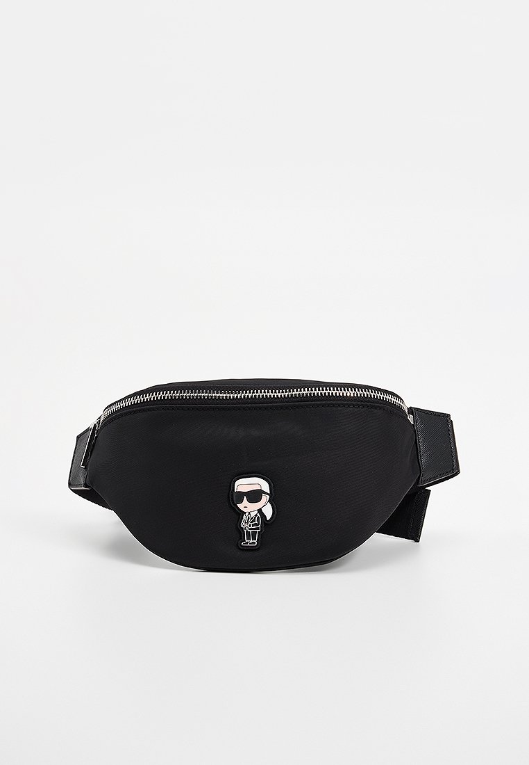 Sac banane noir en nylon avec une texture lisse, fermeture éclair argentée et un patch de personnage de dessin animé à l'avant. Sangle réglable incluse.