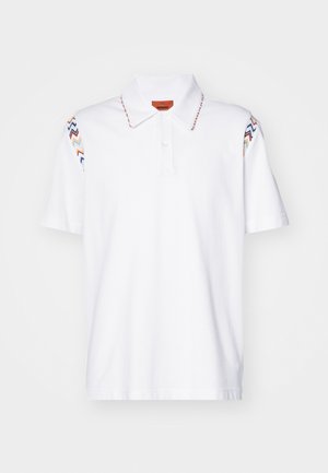 Hvit polo skjorte laget av bomull, med fargerik sikksakk-broderi på ermene og en knappet krage med en merkelapp.
