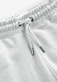 Hellgraue Sweatpants mit elastischem Bund und Kordelzug, ausgestattet mit metallischen Spitzen und einem weichen, strukturierten Stoff.