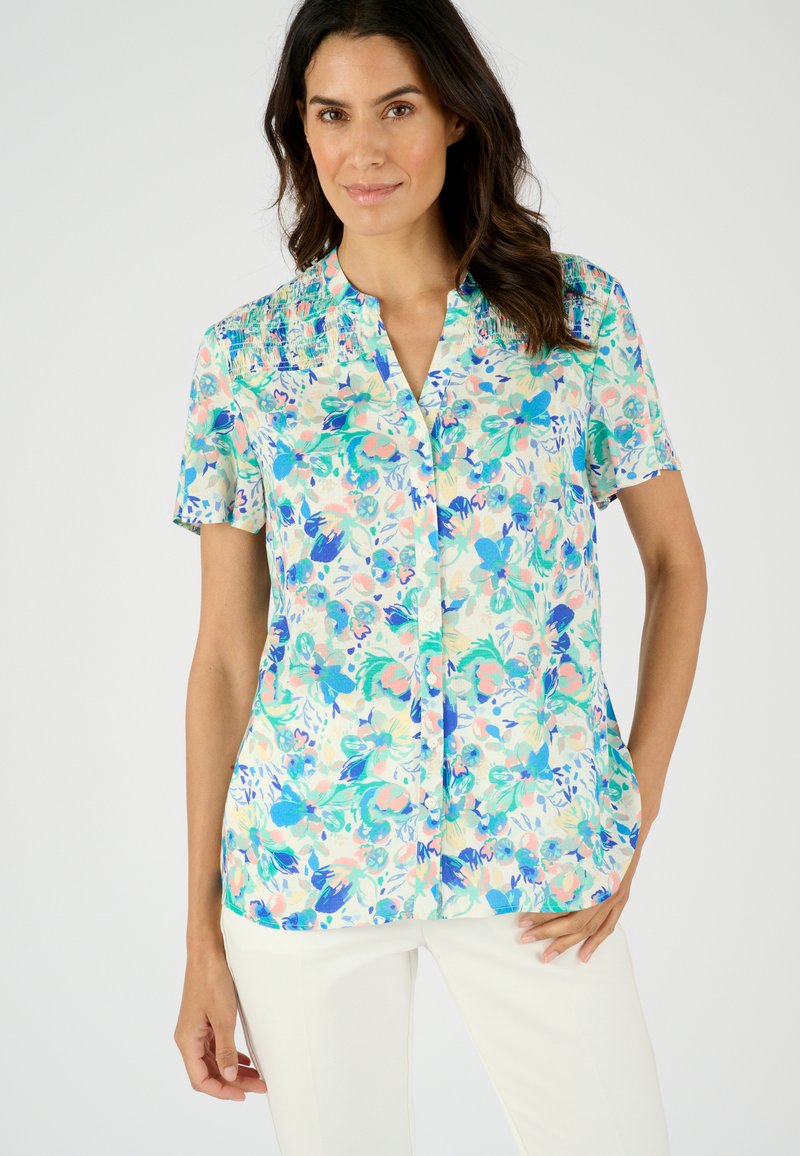 Korte mouw blouse van lichte stof, met een bloemenpatroon in blauw, groen en roze, met een kraag en een knoopsluiting aan de voorkant.
