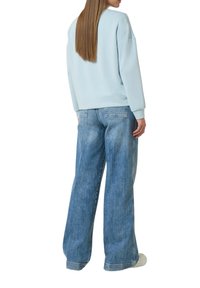 Lichtblauwe sweatshirt met een relaxed fit en geribbelde manchetten, gecombineerd met losse lichtblauwe denim jeans met achterzakken.