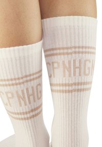 Calzini bianchi al ginocchio in materiale a coste, con un motivo stampato color taupe che presenta il testo "CPNHGN" e strisce di accento.