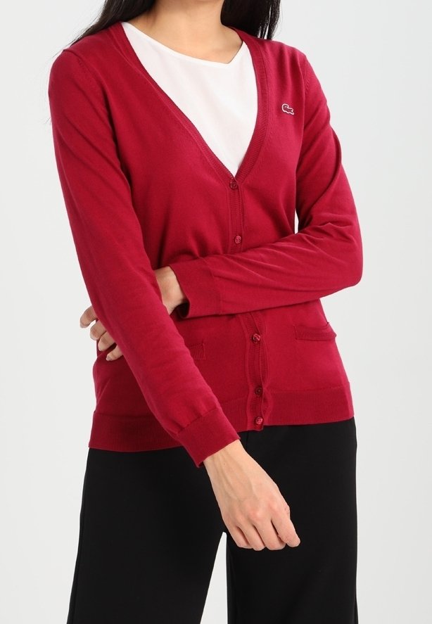Red cardigan made of lightweight fabric, featuring a v-neck, button closure, pockets, and a small logo accent. Long sleeves and fitted design.