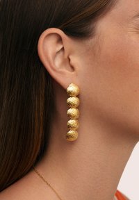Ohrringe im Goldton mit fünf strukturierten, muschelförmigen Anhängern, die in vertikaler Linie hängen und eine glänzende Oberfläche haben.