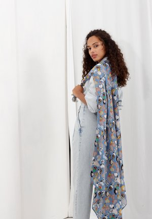 Lichtblauwe sjaal met cartoonfiguren en een gladde textuur. Hij valt elegant en wordt gedragen over een denim outfit.
