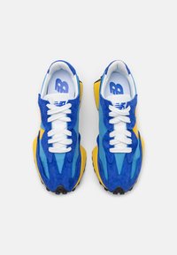 Blue and yellow athletic shoes with a suede and mesh upper, white laces, and a textured rubber sole. Features a logo on the tongue.