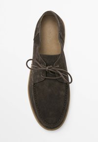 Brown suede lace-up shoe with a rounded toe, visible stitching, and a light brown rubber sole. Flat laces tied at the front.